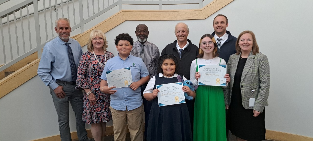 Three youth award recipients standing with their certificates next to the Tooele City Mayor and City Council.